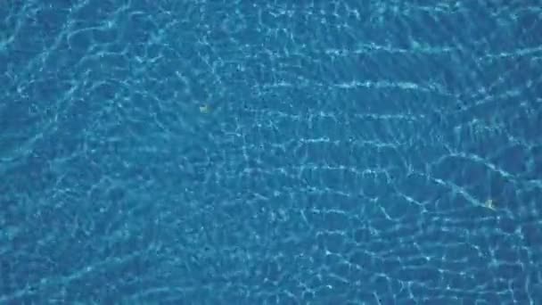 Μπλε του καθαρού νερού στην πισίνα με τις αντανακλάσεις του φωτός. Εναέρια πλάνα — Αρχείο Βίντεο