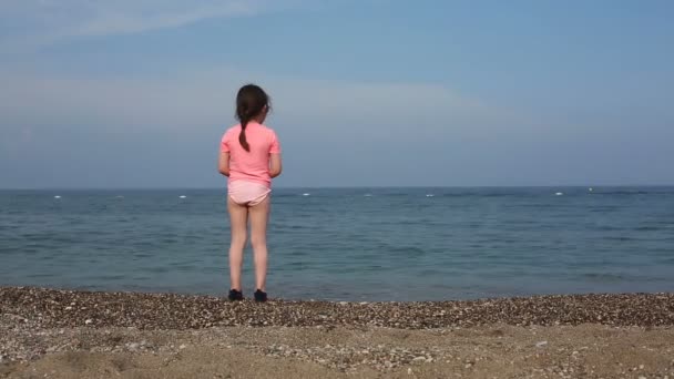 Hermosa chica arrojando piedras al mar — Vídeos de Stock