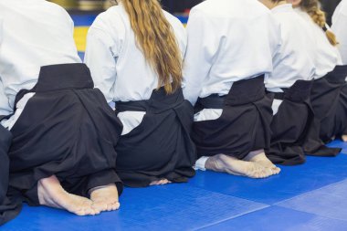 Kimono ve hakama giymiş insanlar dövüş sanatları eğitimi alıyorlar.