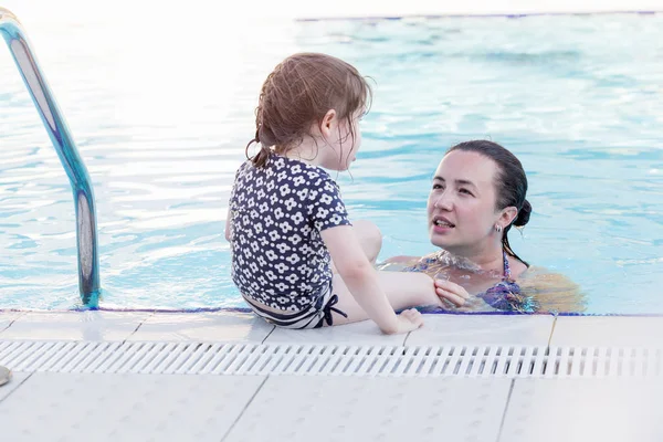 Feliz madre y su hija jugando en la piscina — Foto de Stock