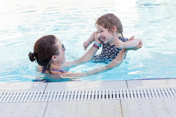 Feliz madre y su hija jugando en la piscina — Foto de Stock