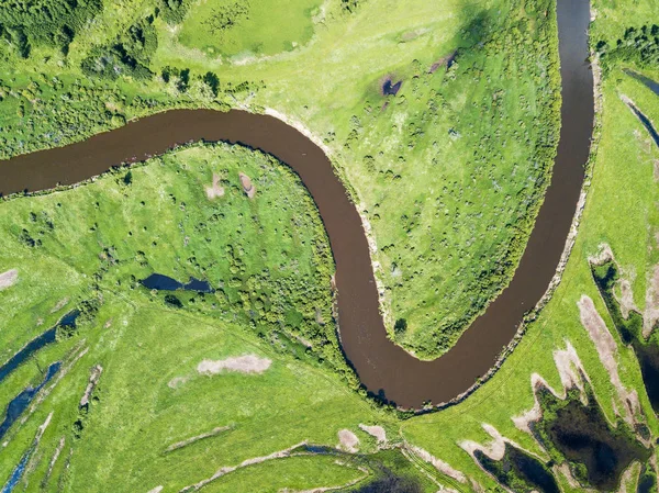 Воздушный ландшафт извилистой реки в зеленых полях — стоковое фото
