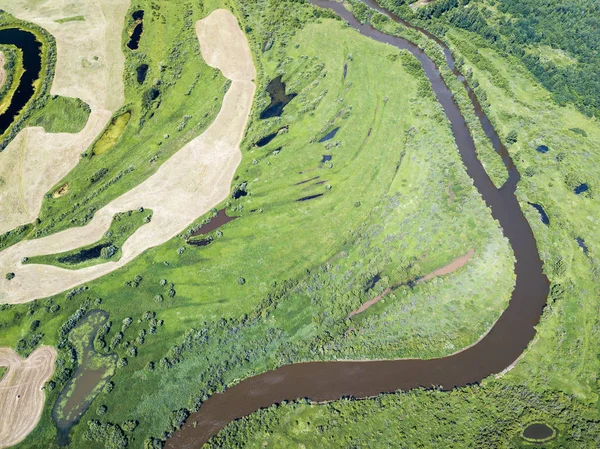 Воздушный ландшафт извилистой реки в зеленых полях — стоковое фото