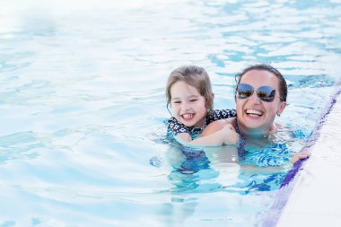 Mutlu anne ve kızının oynarken yüzme havuzunda