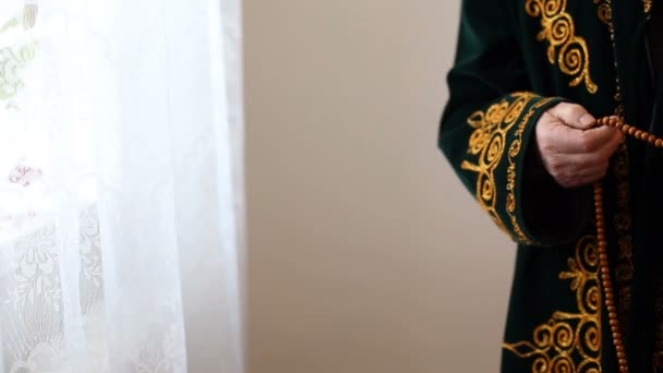 Um mulá velho no vestido nacional que reza com contas de rosário em mãos — Vídeo de Stock