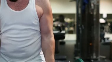 Güçlü bir adam, vücut geliştirici spor salonunda egzersiz yapıyor.