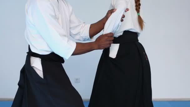 Duas pessoas em hakama preto praticar Aikido no treinamento de artes marciais — Vídeo de Stock