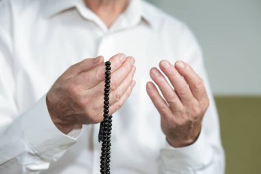 Tespih taşıyan yaşlı bir adamın dua eden elleri.