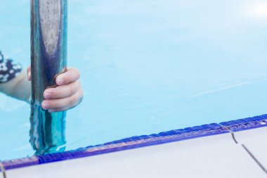 Yüzme havuzunda bir Küpeşte tutan bir el