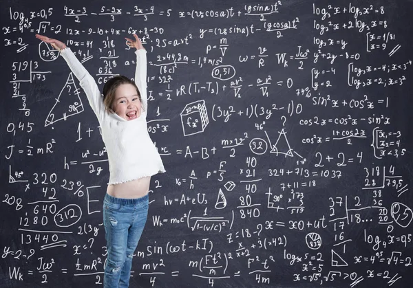 Una niña frente a la pizarra con fórmulas y cálculos — Foto de Stock