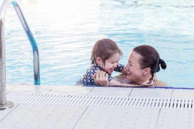 Mutlu anne ve kızının oynarken yüzme havuzunda