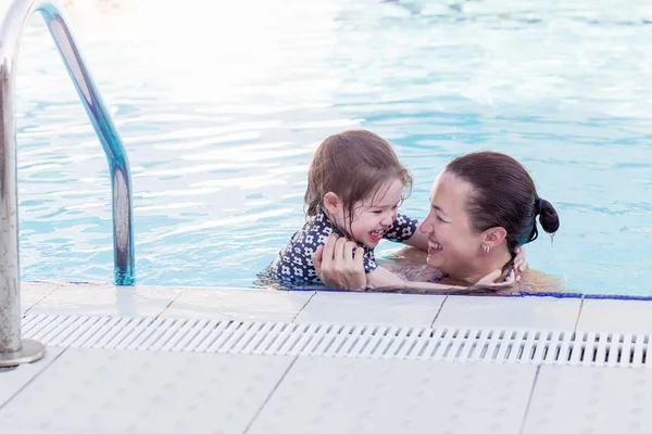 Feliz madre y su hija jugando en la piscina — Foto de Stock