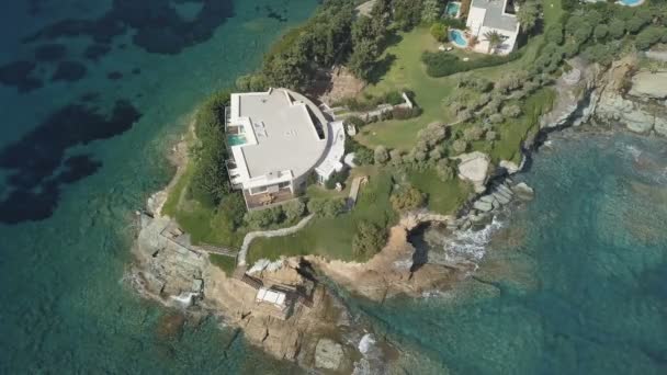 Luchtfoto van de afgelegen villa op de Kaap omringd door de transparante turquoise zee, rotsachtige kust — Stockvideo