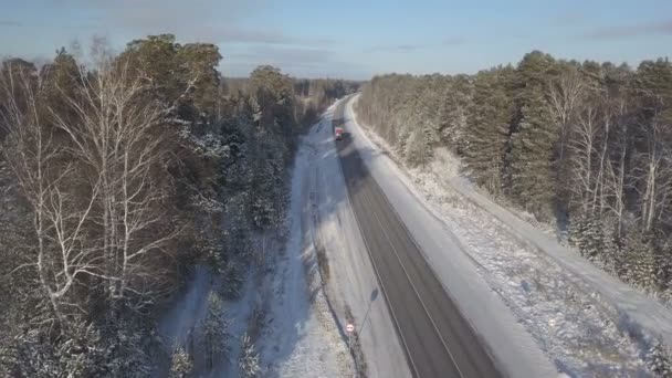 Vrachtwagens rijden langs de weg van de winter met sneeuw bedekt bomen luchtfoto — Stockvideo