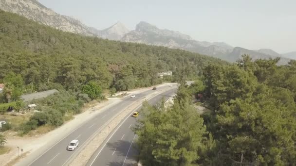Vista aérea de los coches que conducen en la carretera de montaña por el mar — Vídeo de stock