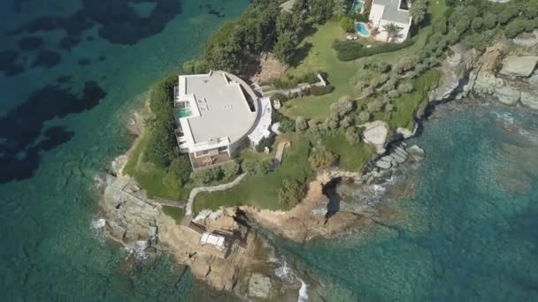 Luchtfoto van de afgelegen villa op de Kaap omringd door de transparante turquoise zee, rotsachtige kust — Stockvideo