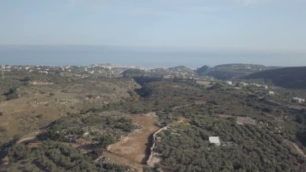 Śródziemnomorski krajobraz z zielonego wzgórza z drzewami oliwnymi. Błękitne morze na panoramę miasta. Grecja, Crete — Wideo stockowe