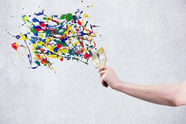 Renkli boya oluşturma boya fırçası tutan bir el su sıçramalarına — Stok fotoğraf