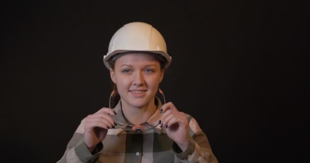 Eine Ingenieurin lächelt auf schwarzem Hintergrund — Stockvideo