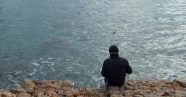 Balıkçı balıkçılık deniz tarafından. Arka arkadan görünüm