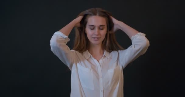 Une belle jeune femme courant la main à travers ses cheveux — Video