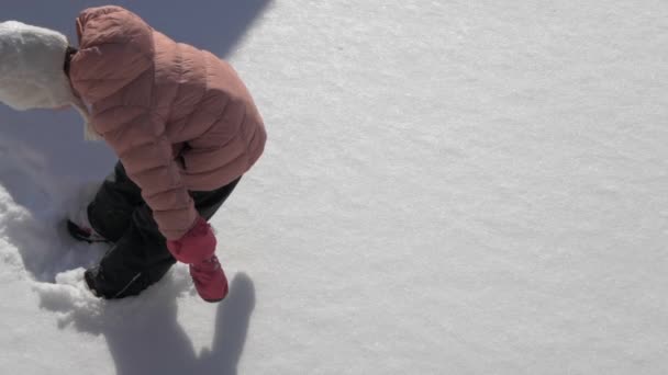 Красивая маленькая девочка делает снежного ангела — стоковое видео
