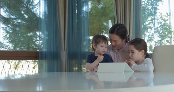 Oma haar weinig kleinkinderen met een tablet-computerspel onderhoudend — Stockvideo