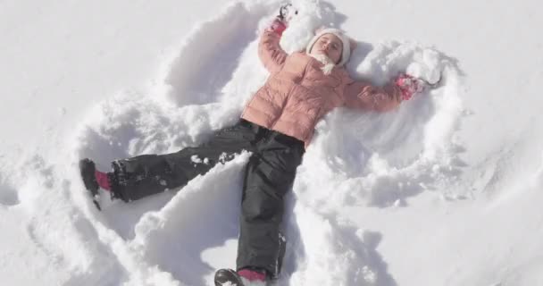 Vacker liten flicka att göra en snöängel — Stockvideo