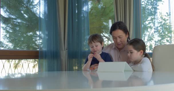 Oma haar weinig kleinkinderen met een tablet-computerspel onderhoudend — Stockvideo