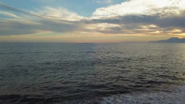 Vacker solnedgång på stranden med gyllene solen speglar på havet och bergen bakgrunden — Stockvideo