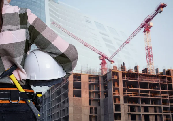 Una mujer trabajadora de la construcción con casco blanco sobre fondo de ciudad — Foto de Stock