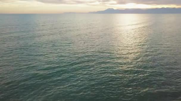 Прекрасний захід сонця на пляжі з відображенням золотого сонця на морському і гірському тлі — стокове відео