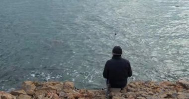 Balıkçı balıkçılık deniz tarafından. Arka arkadan görünüm