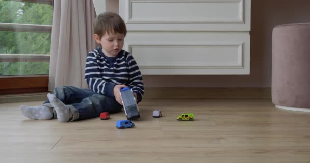 Menino brinca com carros uma casa — Vídeo de Stock