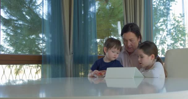 Grandma entertaining her little grandchildren with a tablet computer game — Stock Video