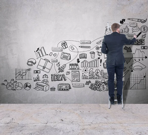 Homem desenhando um plano de negócios em uma parede de concreto — Fotografia de Stock