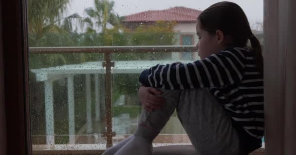 下雨天, 一个小女孩坐在窗边 — 图库视频影像