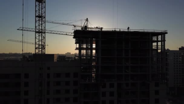 日没時の建設現場。建物の近くの建設用クレーンのシルエット — ストック動画