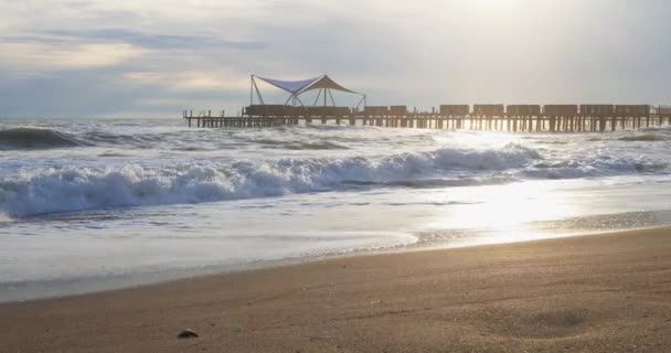 Schöner Sonnenuntergang am Strand mit goldener Sonnenreflexion über dem Meer und der Bergkulisse — Stockvideo