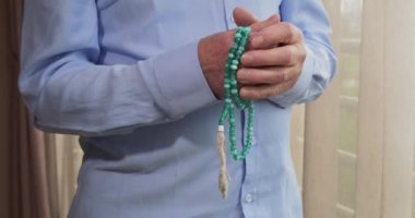 Tespih taşıyan yaşlı bir adamın dua eden elleri.