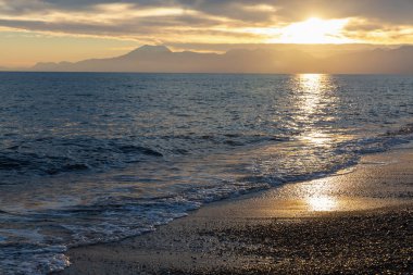 Denizde altın güneş yansıması ile plajda güzel gün batımı
