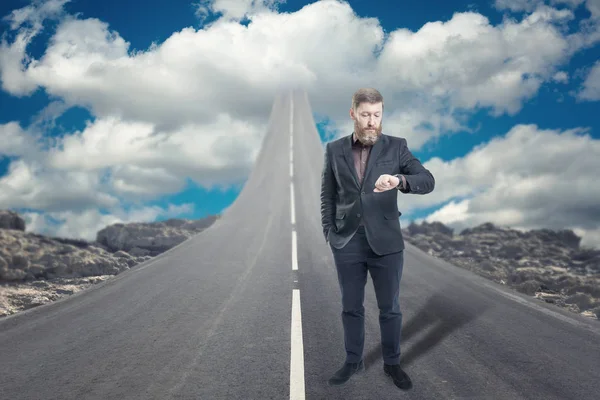 Бізнесмен стоїть на дорозі, яка піднімається в небо — стокове фото
