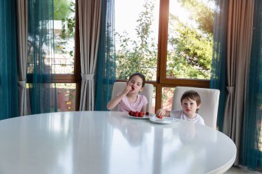 Evde taze olgun çilek yiyen tatlı çocuklar.