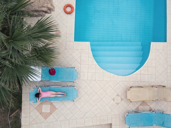 Little girl sunbathing by a swimming pool — Stock Photo, Image