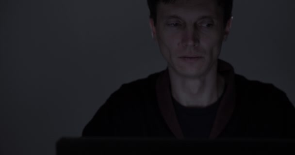 Porträt eines müden Mannes, der spät in der Nacht im dunklen Raum am Laptop arbeitet — Stockvideo