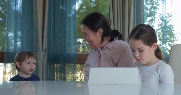 Oma haar weinig kleinkinderen met een tablet-computerspel onderhoudend — Stockvideo