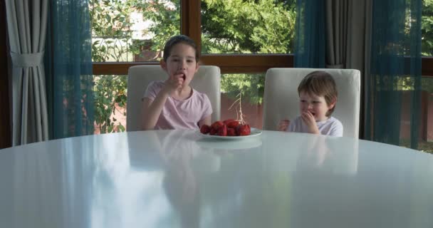Lindos niños comiendo fresas frescas maduras en casa — Vídeos de Stock