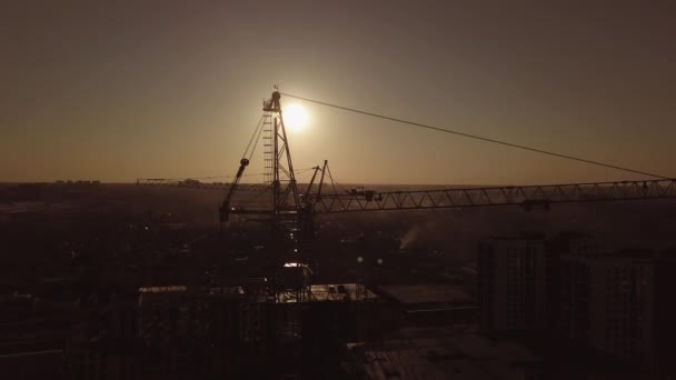 Sitio de construcción al atardecer. Silueta de una grúa de construcción cerca del edificio — Vídeos de Stock