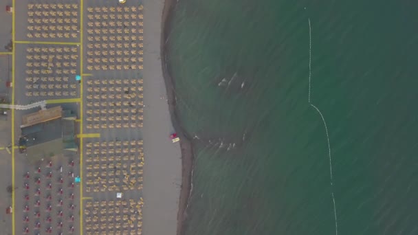 Vista aérea da praia de areia com espreguiçadeiras amarelas e guarda-sóis de madeira ao pôr do sol — Vídeo de Stock