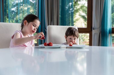 Evde taze olgun çilek yiyen tatlı çocuklar.